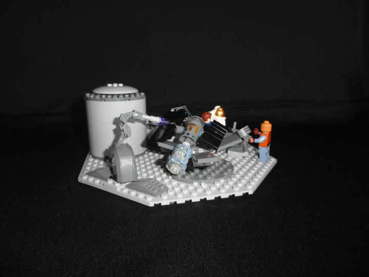LEGO MOC - Because we can! - Forward to the stars!: Как я говорил выше, раз уж мы готовы потратить огромный деньги на этот полёт, почему бы не сделать что нибудь полезное, например, вывести на земную орбиту спутник, который позволит точнее предсказывать погоды, составлять карту в реальном времени, доставлять кабельное в ваши дома или просто следить за всеми вами?<br />
Удобная вещь, не правда ли?<br />
Инженер, скромно стоящий за пультом управления дорабатывает систему, позволяющую  позволяющую спутнику накапливать космическую энергию, чтобы обеспечить бесперебойное функционирование всех систем (спустя много лет эти наработки приведут к созданию гибких солнечных батарей), но пока это лишь идея.<br />

